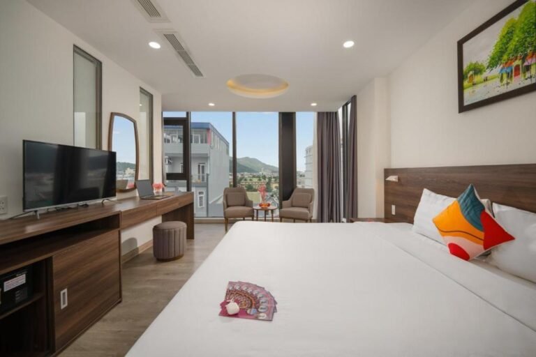 Phòng nghỉ khách sạn Mira Quy Nhơn với cửa sổ kính lớn nhìn ra thành phố